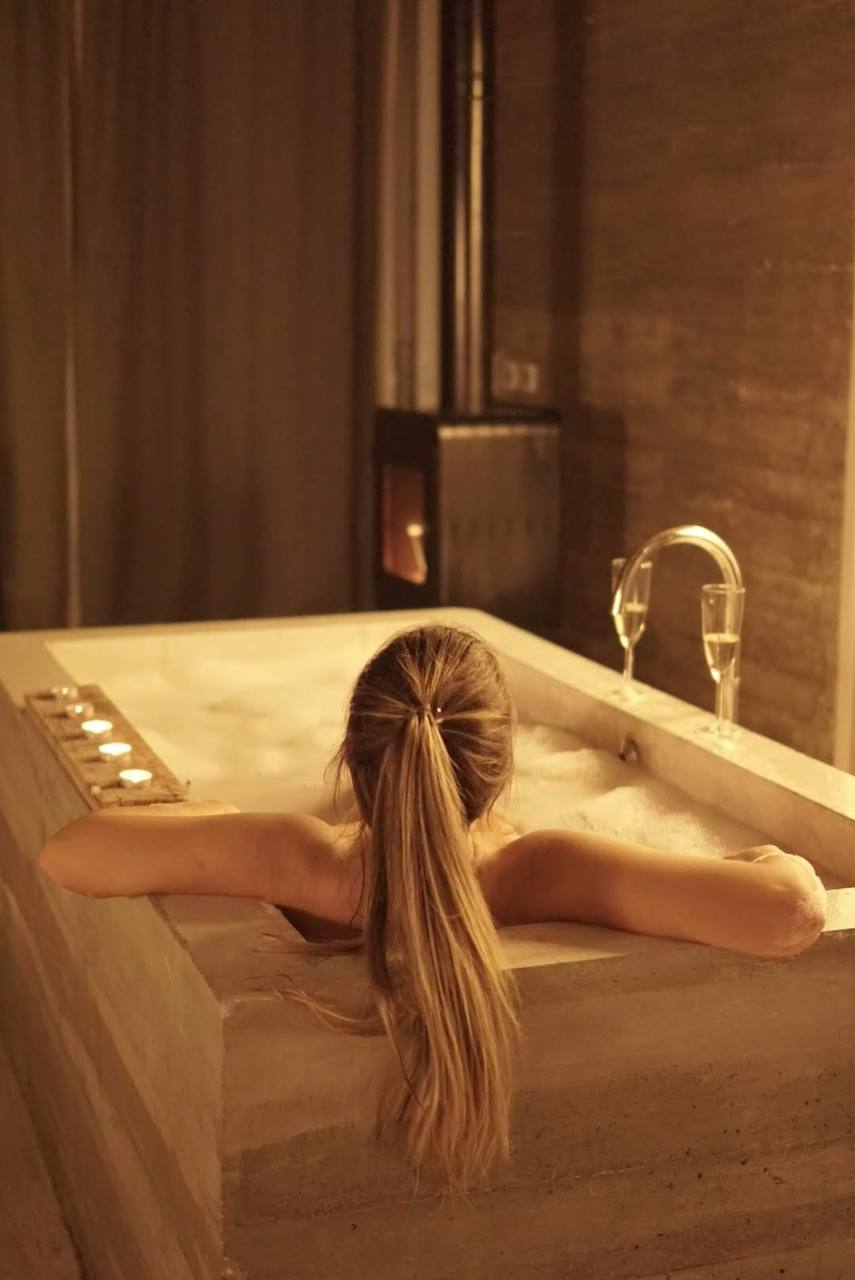 Candlelit bathtub with champagne glasses in a stone bathroom