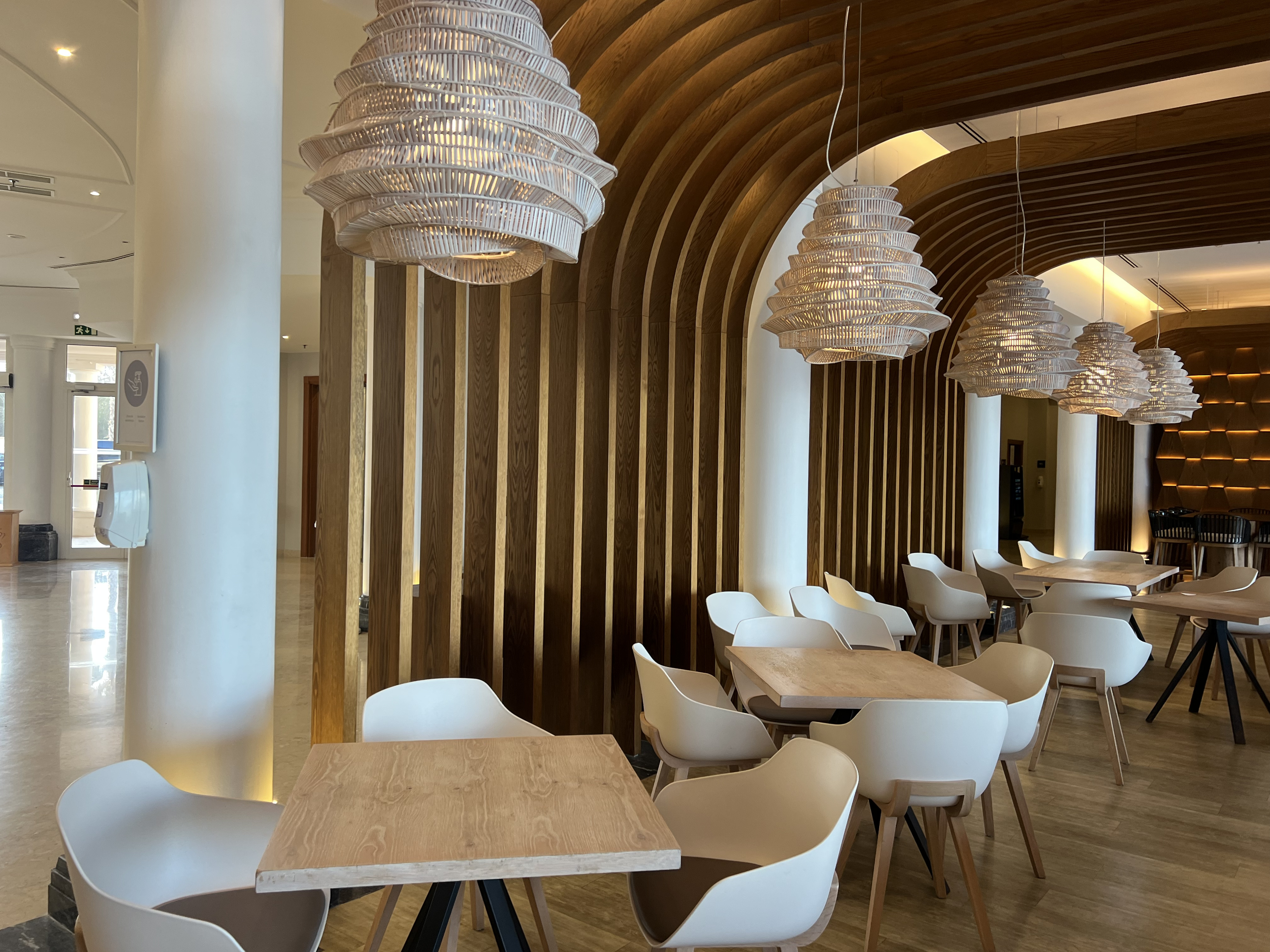 Hotel dining area with woven pendant lamps and arched wooden walls