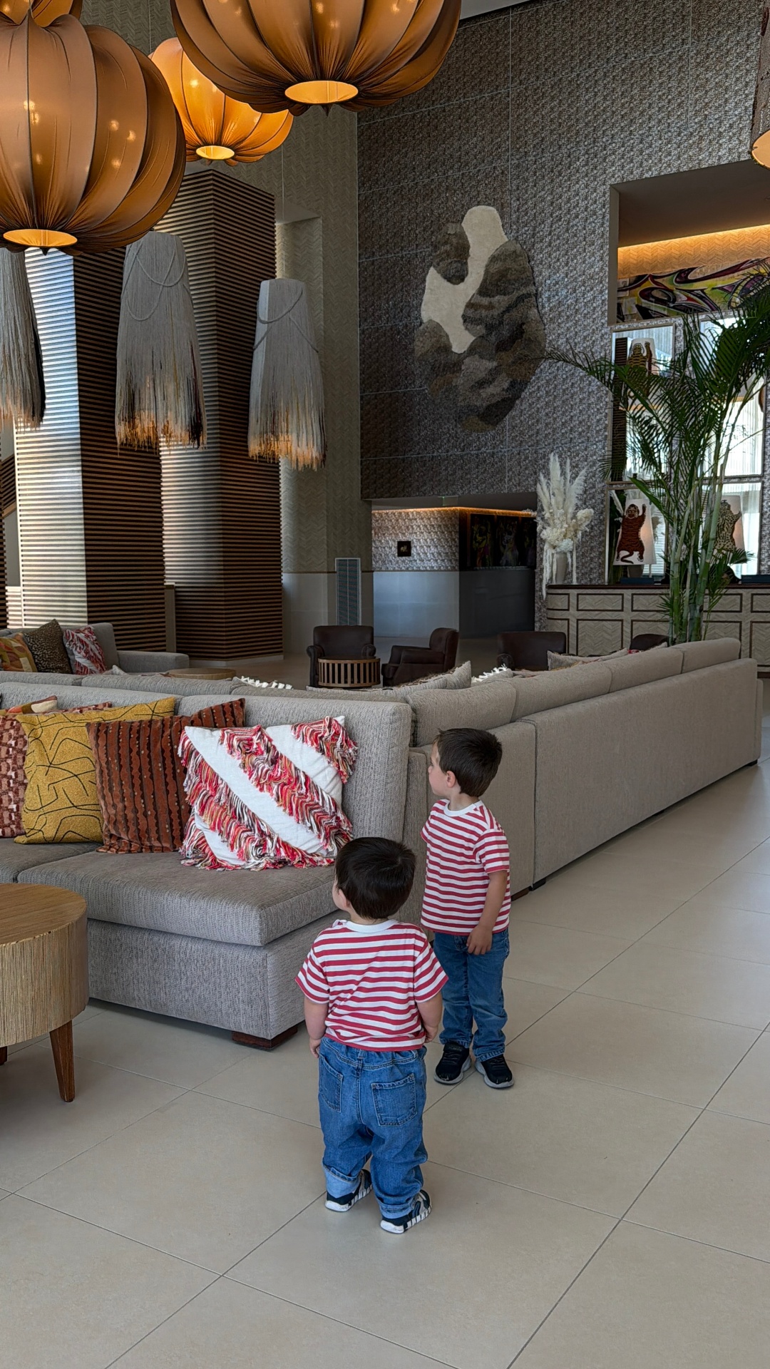 Two brothers in striped shirts exploring a design hotel lobby