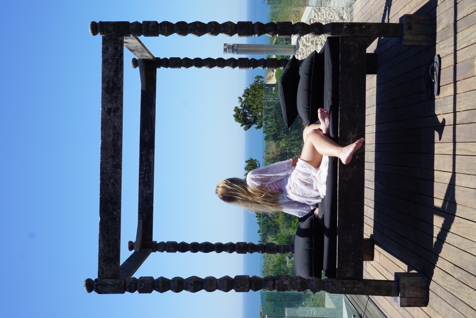 Woman sitting on a canopy daybed overlooking the ocean